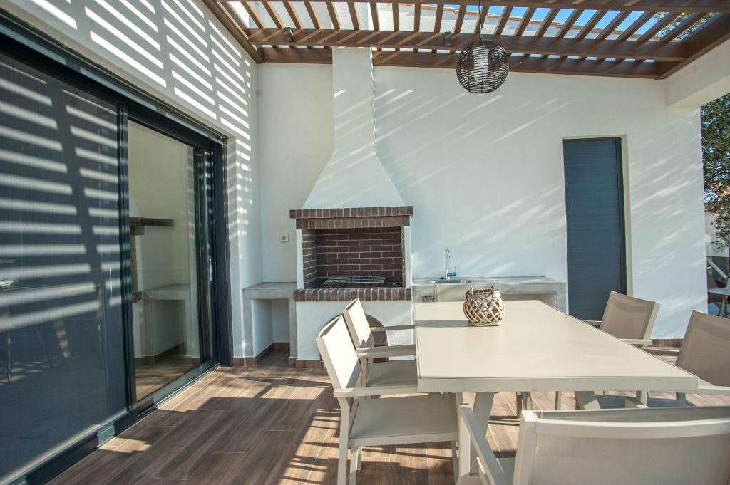 Villa Carisma outdoor dining area with BBQ under a pergola, Kefalonia