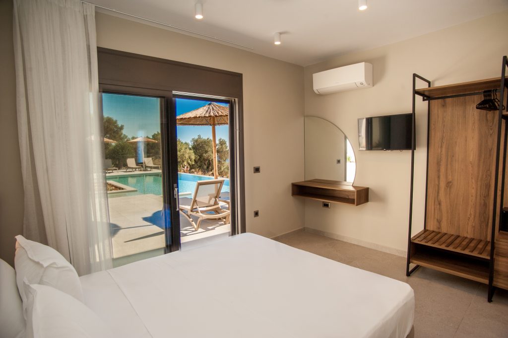 Villa Insieme bedroom with pool-view terrace and wall-mounted TV, Kefalonia